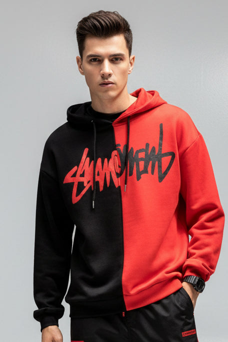 Person wearing a black and red hoodie with a brand logo on a dark background