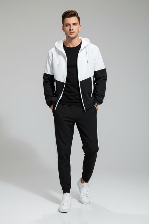 Man wearing a black and white color-blocked tracksuit on a gray background