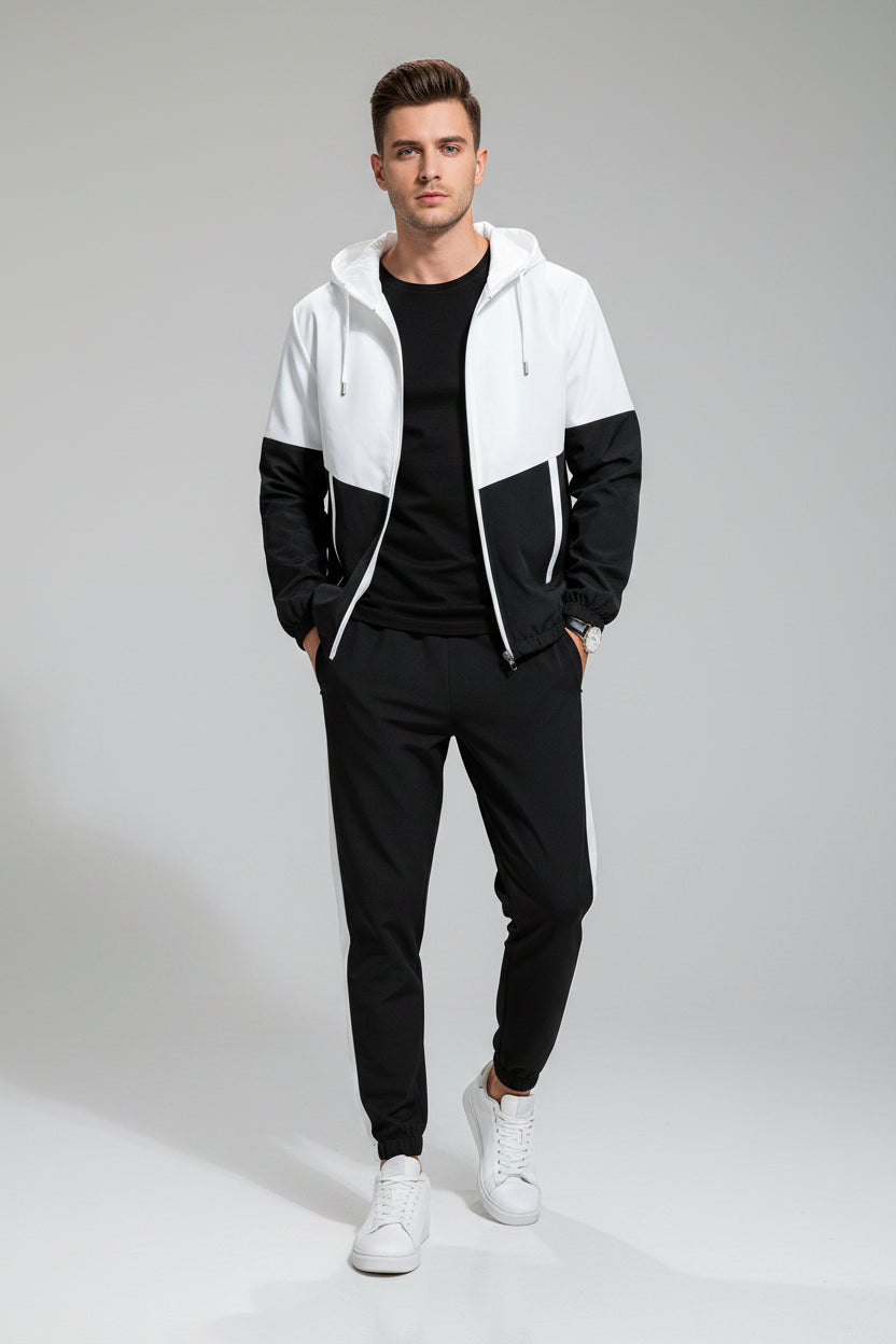 Man wearing a black and white color-blocked tracksuit on a gray background