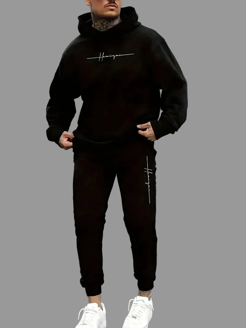 Man wearing a black hoodie and pants with a logo on a street.