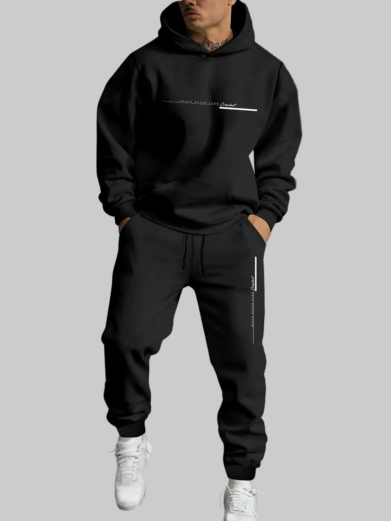 Person wearing a black hoodie and jogger pants with white sneakers against a gray background