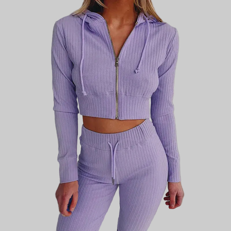 Person wearing a purple ribbed tracksuit on a white background