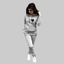 Woman wearing a gray hoodie and pants set with a heart design on a plain background