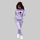 Woman wearing a lavender tracksuit against a gray background