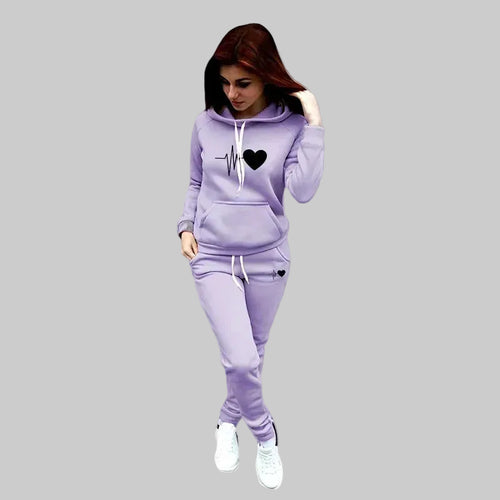Woman wearing a lavender tracksuit against a gray background