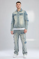 Person wearing a patchwork denim jacket and jeans on a gray background