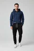Blue hoodie with front pockets and a person wearing black pants and white sneakers on a gray background