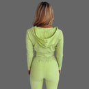 Person wearing a green ribbed knit outfit against a white curtain background
