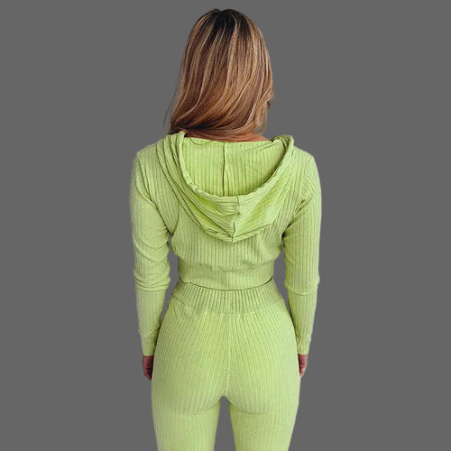 Person wearing a green ribbed knit outfit against a white curtain background