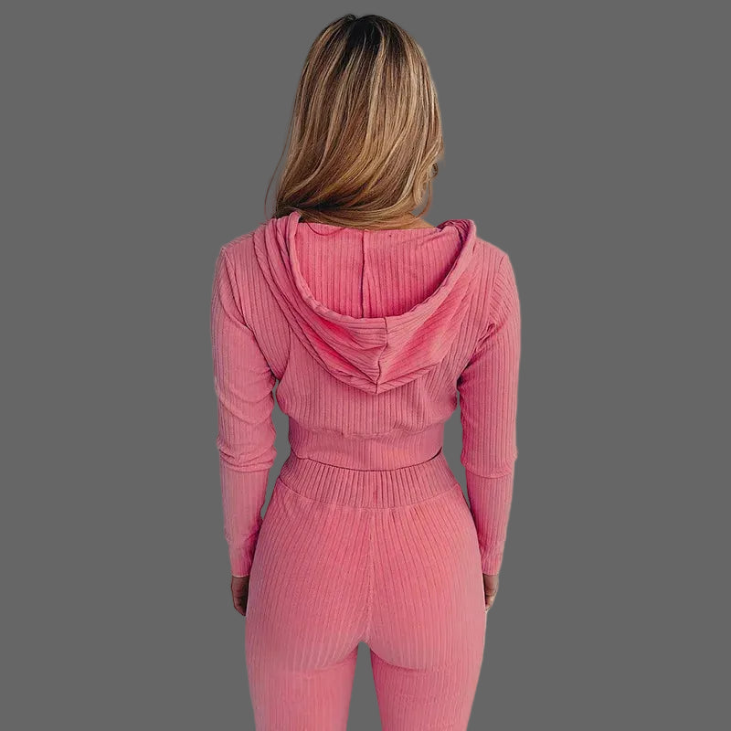 Person wearing a pink ribbed knit outfit with a hood against a white background