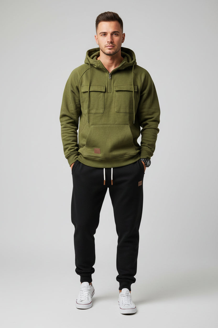 Green hoodie with front pockets and a person wearing black pants and white sneakers on a gray background