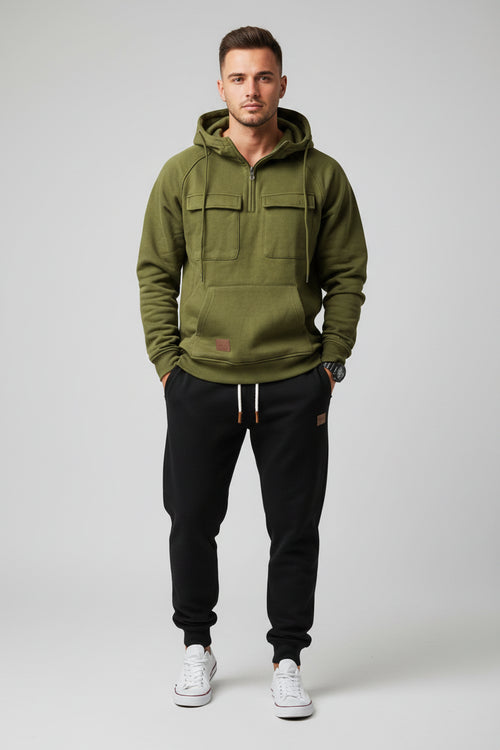 Green hoodie with front pockets and a person wearing black pants and white sneakers on a gray background