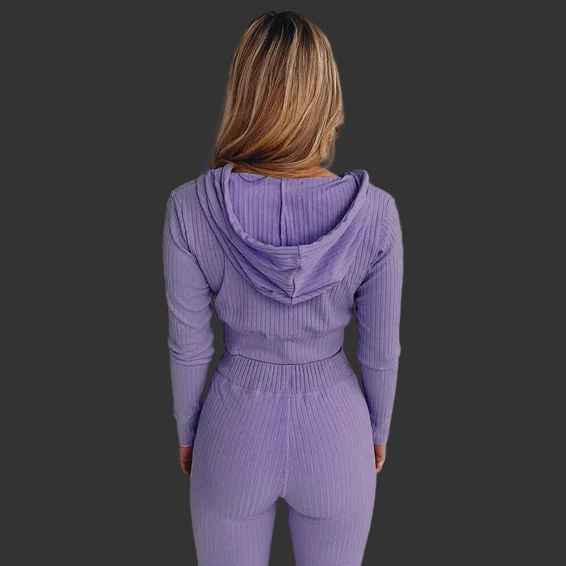 Person wearing a purple ribbed hoodie and pants set against a white background