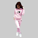 Woman wearing a pink tracksuit with a heart design on a gray background