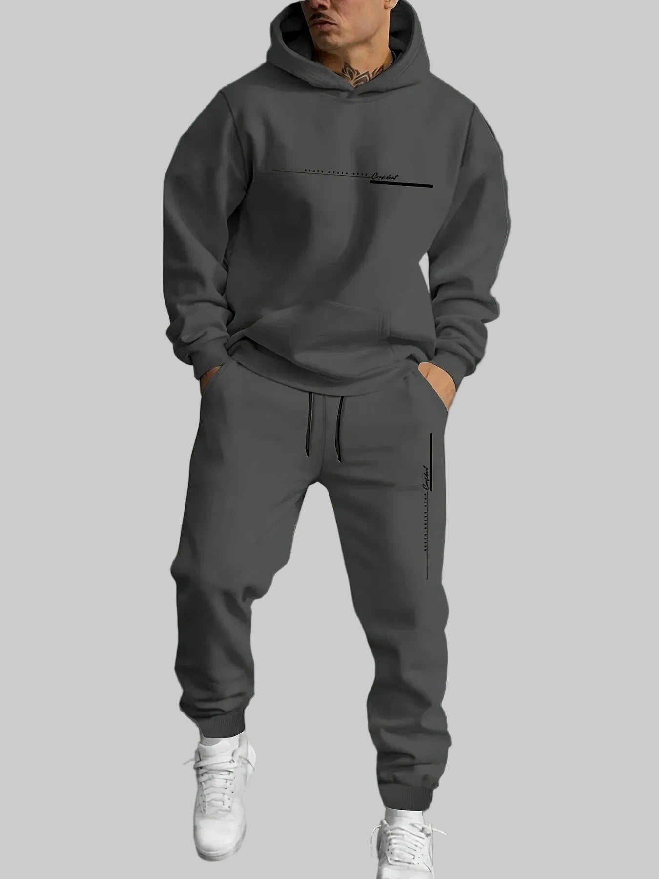 Person wearing a gray hoodie and pants set with a logo on a dark background