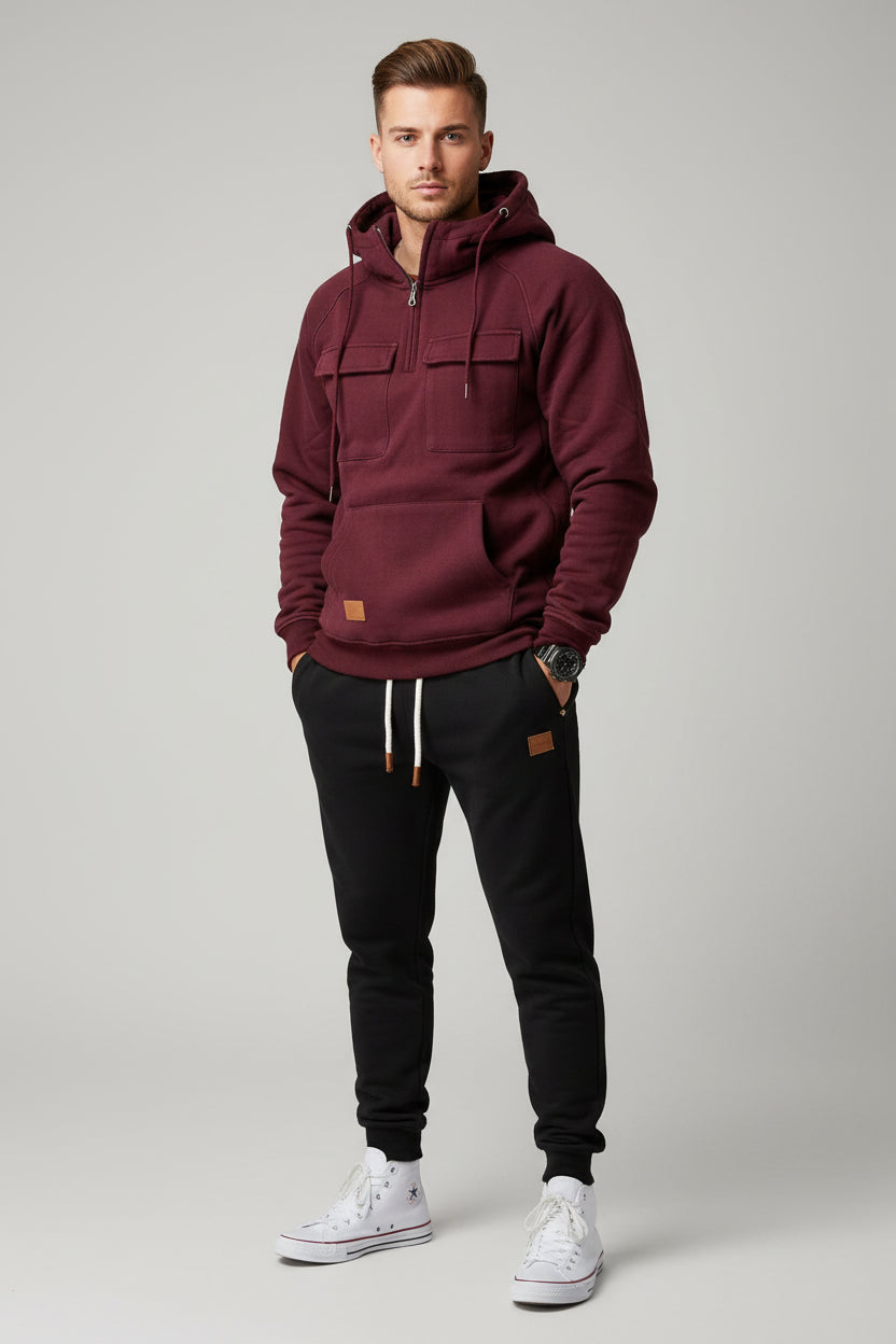Maroon hoodie with front pockets and a person wearing black pants and white sneakers on a gray background